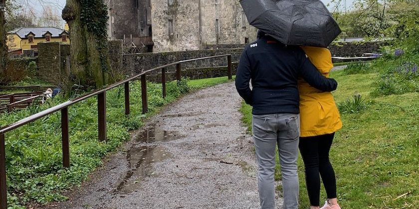 Couple under umbrella looking at a castle