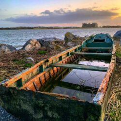 Old waterlogged boat on the side of the river